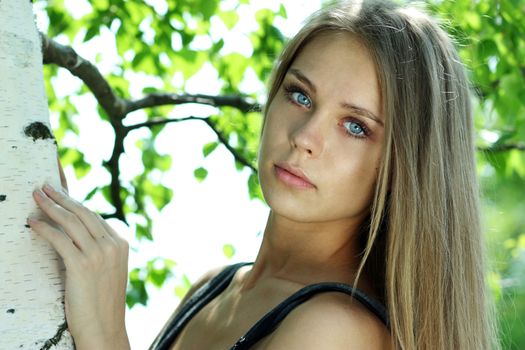 Portrait of the young beautiful woman on a background of leaves of a birch