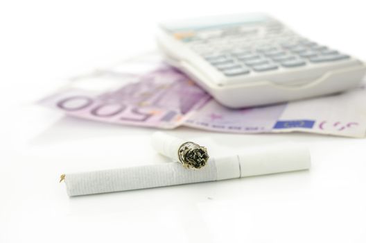 Cigarettes with Euro money and calculator in background. Concept of costs of smoking.