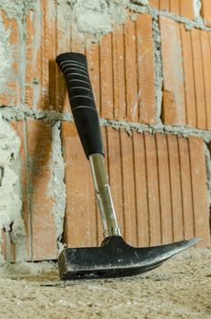 Hammer leaning on brick wall on construction site. Concept of building a house.