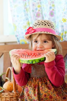 little girl in a straw hat with appetite eats a ripe water-melon