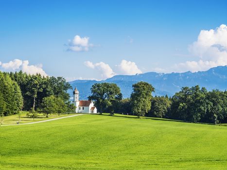 Typical chapel on grean meadow with alps and trees in Bavaria