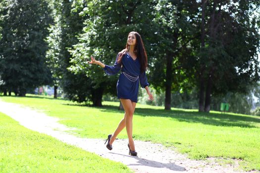 Beautiful young woman walking on the summer park