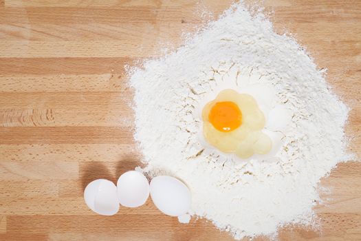 egg in flour from top with egg and broken egg aside on wooden background