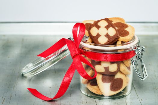 a jar filled with christmas cookies on a silver metal tray