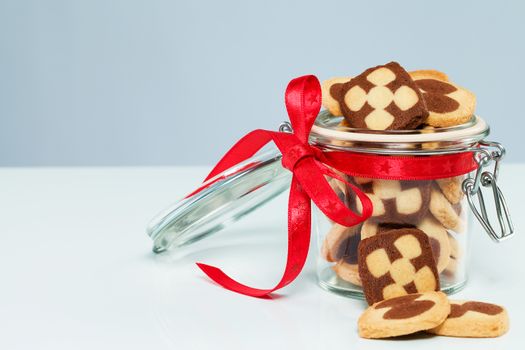 christmas cookies in a glass jar with cookies aside with blueish background