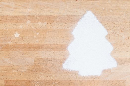 flour in shape of a christmas tree with copy space and stars on wooden background