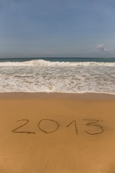 2013 written in sand on beach with sea waves 
