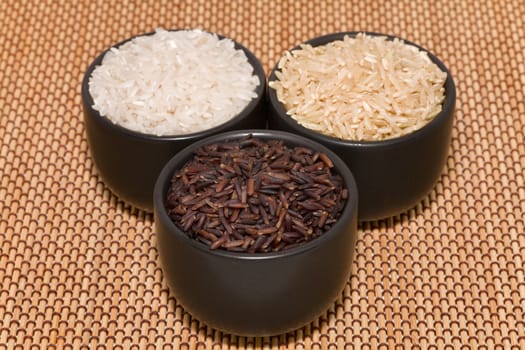 raw black, brown and white rice in bowls