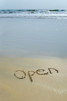 Sea and Handwriting word Open written  on the sand 