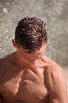 Wet young atletic man showing biceps
