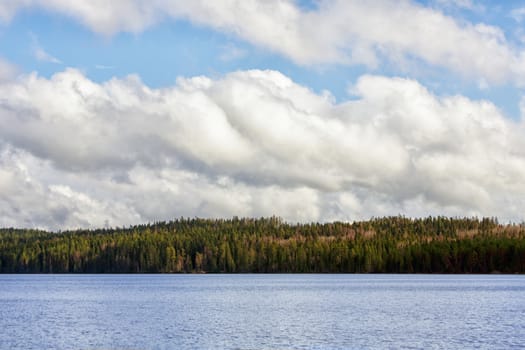 Summer landscape with river and clouds on blue sky.