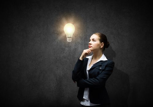Image of thoughtful businesswoman looking at light bulb