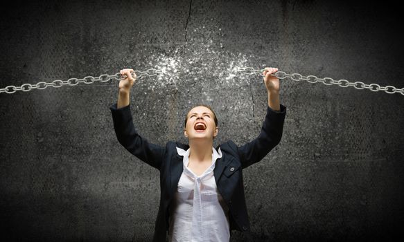 Image of businesswoman in anger breaking metal chain