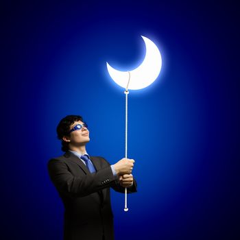 Image of young businessman in goggles looking at moon