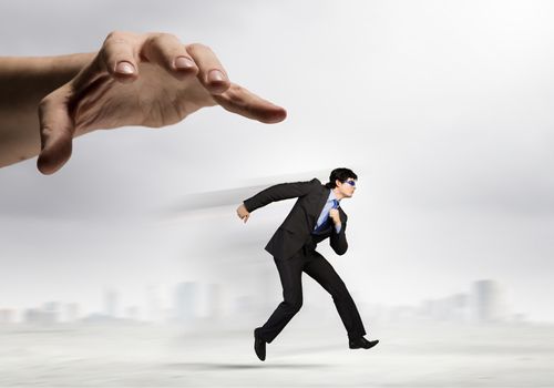 funny image of businessman trying to run away from hand