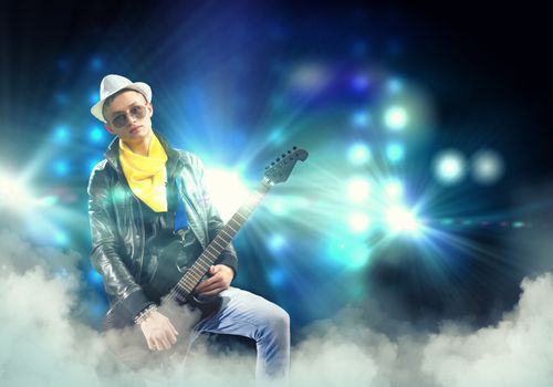 Young man, rock musician in jacket playing guitar