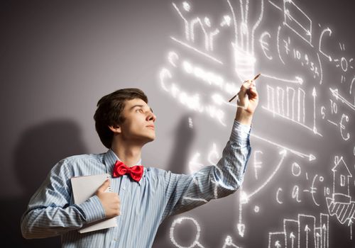 Image of thoughtful male student holding notebook in classroom