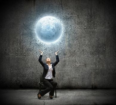 image of businesswoman holding moon in hands above head