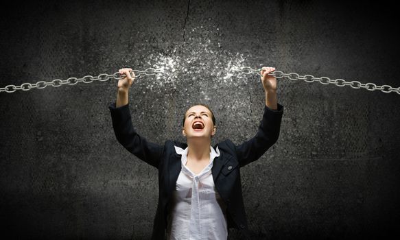 Image of businesswoman in anger breaking metal chain