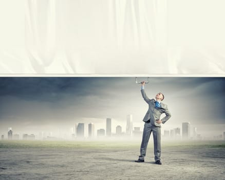 Image of young businessman pulling blank banner from above