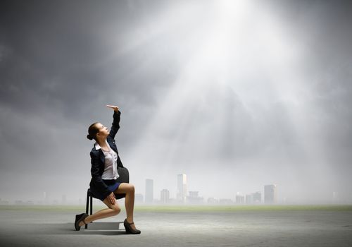 Image of businesswoman sitting on chair under sun lights