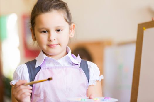 Little cute girl with paint brush and easel