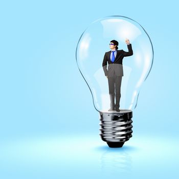 Image of young businessman in light bulb. New idea and inspiration