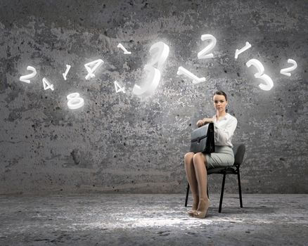 Image of businesswoman sitting on chair with suitcase in hands