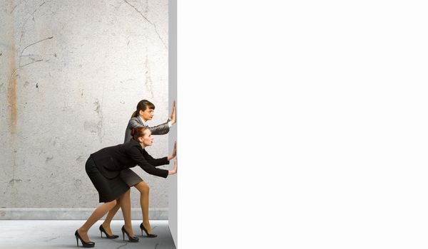 Two businesswoman pushing blank white banner. Place for text