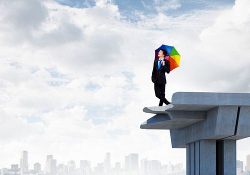 Image of businessman with umbrella standing at the edge of bridge