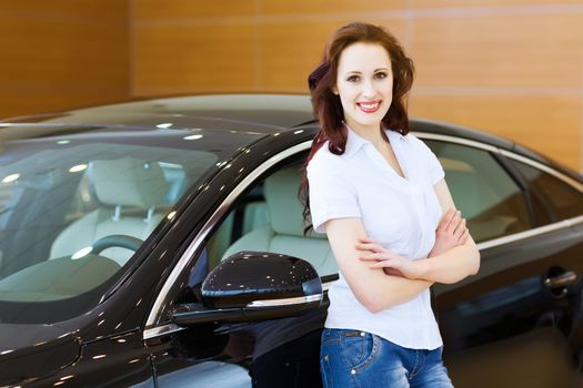 Pretty woman standing near car at car center. Choosing a car