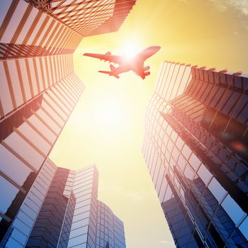 Image of airplane flying above skyscrapers. Bottom view