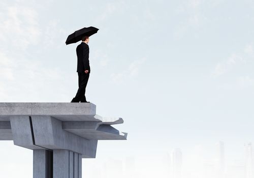 Image of businessman with umbrella standing at the edge of bridge