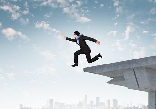 Image of jumping businessman at the edge of bridge