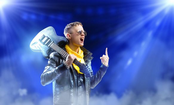 Young man, rock musician in jacket with guitar