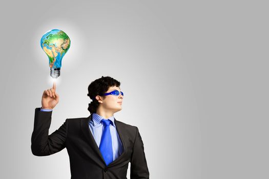 Image of young businessman with light bulb. New idea and inspiration. Elements of this image are furnished by NASA
