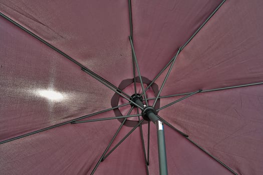  Details of an open brown beach umbrella parasol                            