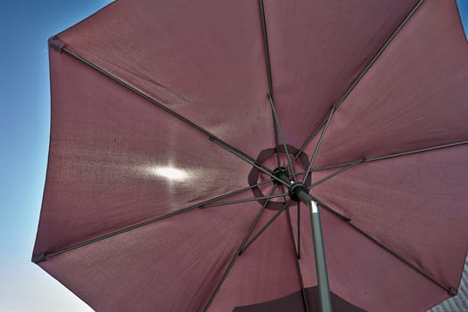 Details of an open brown beach umbrella parasol