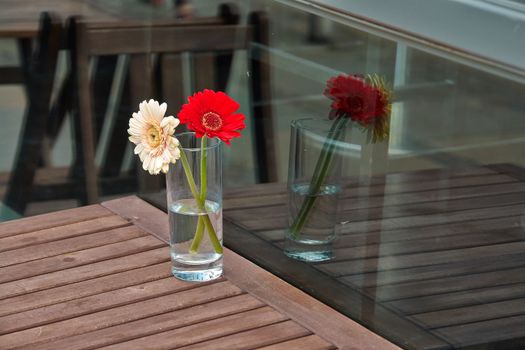  Beautiful flowers bouquet in a glass vase on wooden table of a restaurant                              