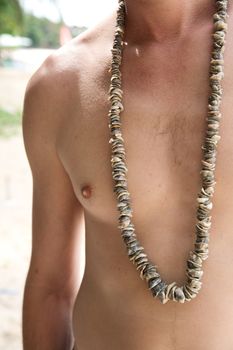 young man with beads of  shellon the beach