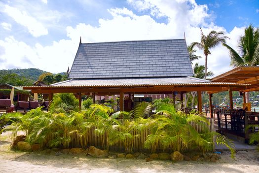 View of tropical beach with house and coconut palm trees 