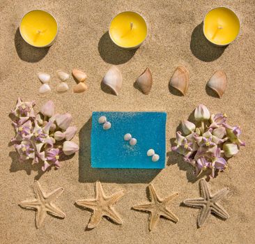 bar of natural handmade soap on sand with flower,  star and shell