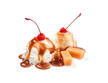 Two icecream balls under the caramel topping with cherry on the top