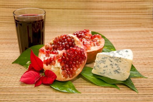 cheese with mold and pomegranate with glass of wine on matting