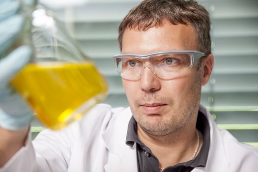A man with a yellow liquid in the laboratory