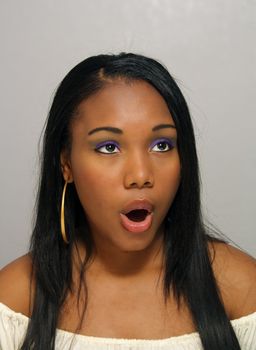 A close-up of a lovely young Haitian girl looking toward the upper frame-right corner and forming an "O" with her mouth.