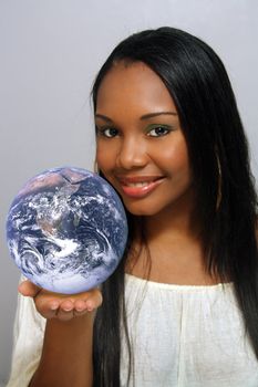 A close-up of a lovely young Haitian girl with a captivating smile, holding a miniature earth in the palm of her hand.