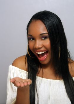 A close-up of a lovely young Haitian girl with a captivating smile and her hand toward the camera, palm up, waiting for you to place your product in it.