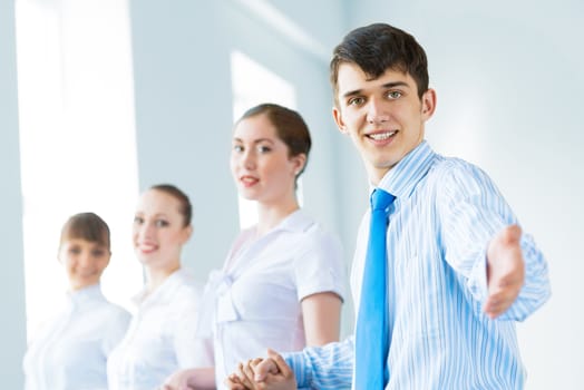 invitation to the team, the business man stretches out his hand, behind him a number of young businessmen