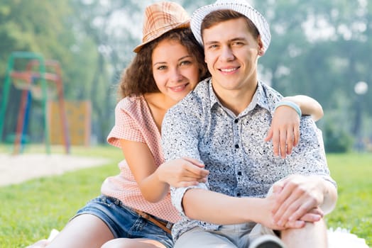 romantic couple lying on the grass in the summer park, spending time with loved ones